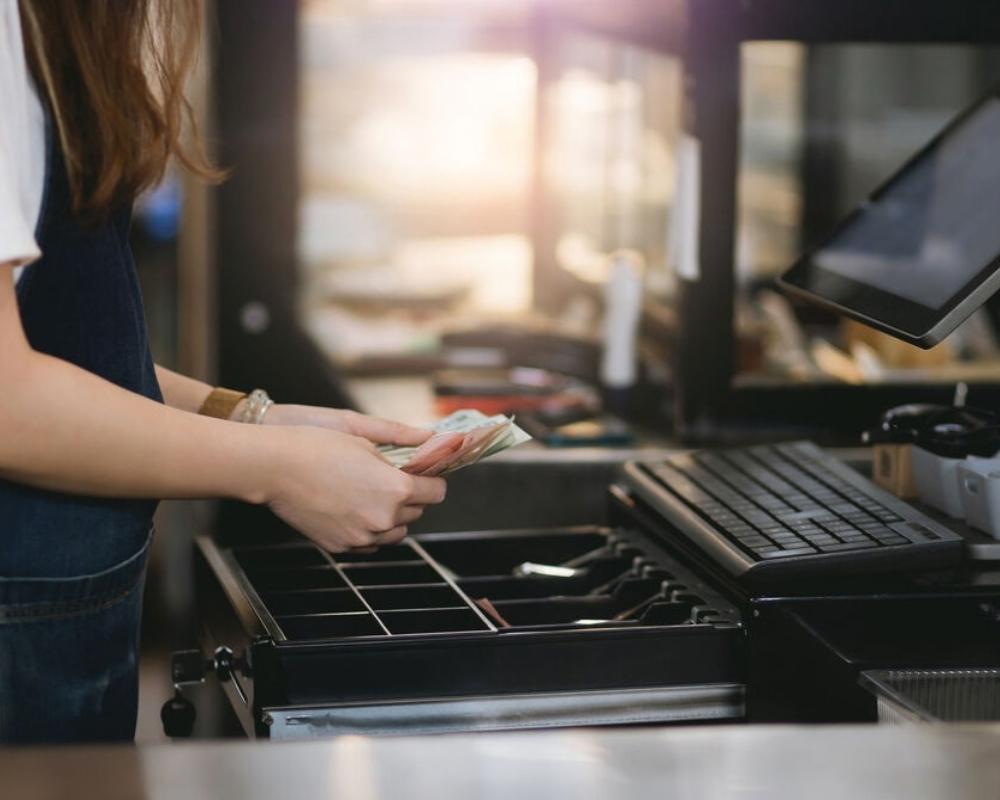 cashier handling cash at Point-of-Sale system POS